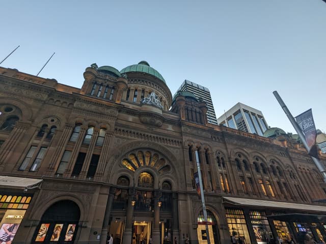 A historic building with ornate architecture, featuring arched windows and a large central dome, set against a clear sky