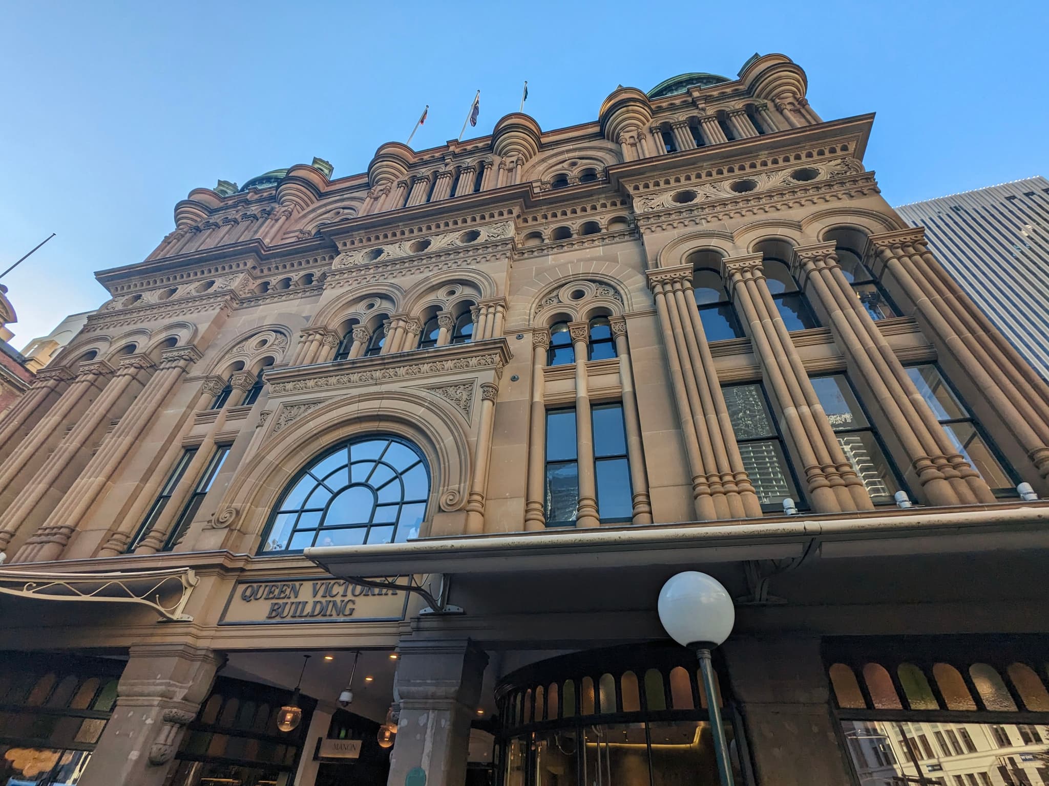 A historic building with ornate architectural details, featuring arched windows and decorative columns, set against a clear blue sky
